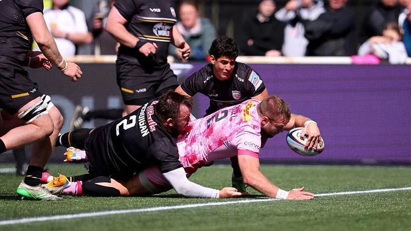 Harlequins hooker Sam Riley (number 2) is about to touch down for a try as George McGuigan (number 2) tries to stop him and Newcastle's Simon Benitez Cruz is crouched and watching